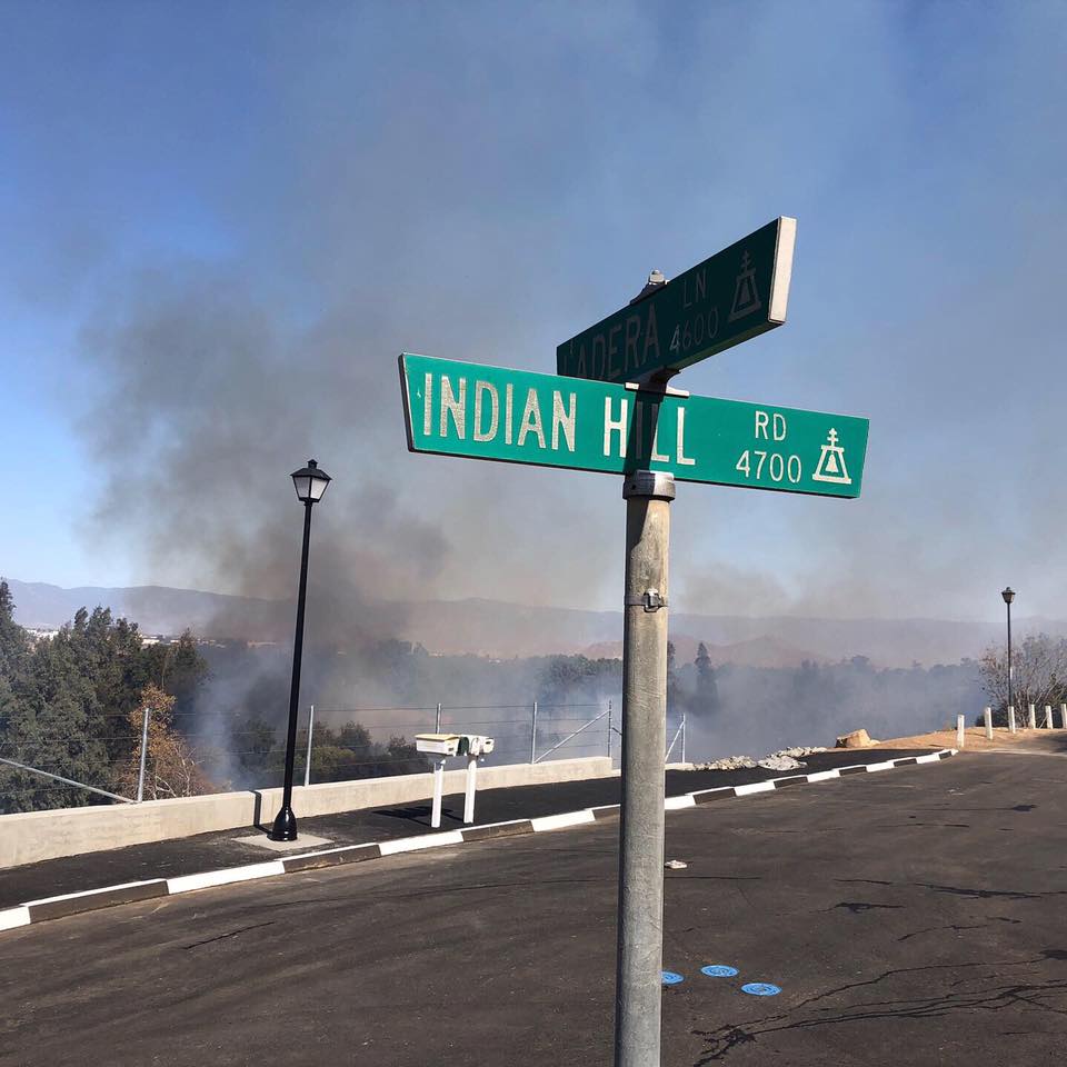 Sign post with street names Indian Hill and Ladera, Smoke in background.