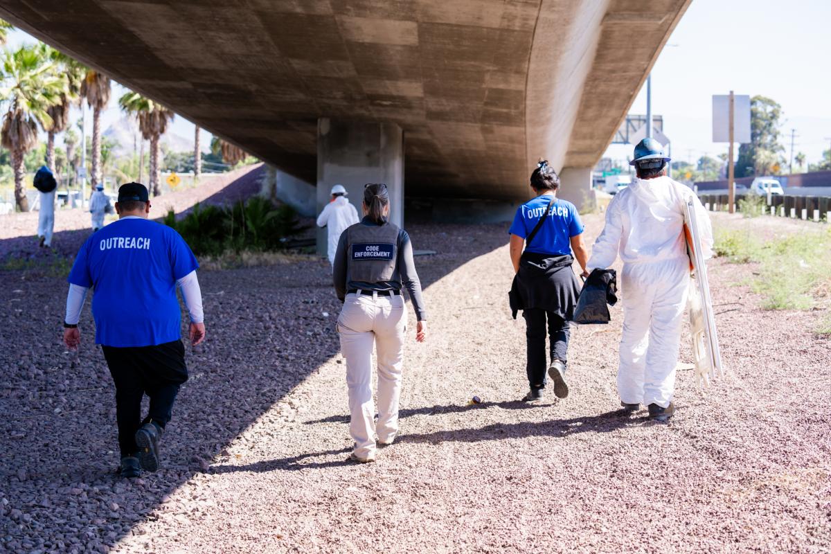 Outreach and code enforcement staff walk beneath an overpass during a City of Riverside and Caltrans partnership outreach effort.