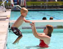 Child jumping into the pool with instructor 