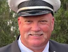 Photo of Captain Tim Strack in Class A uniform, hat, and tie